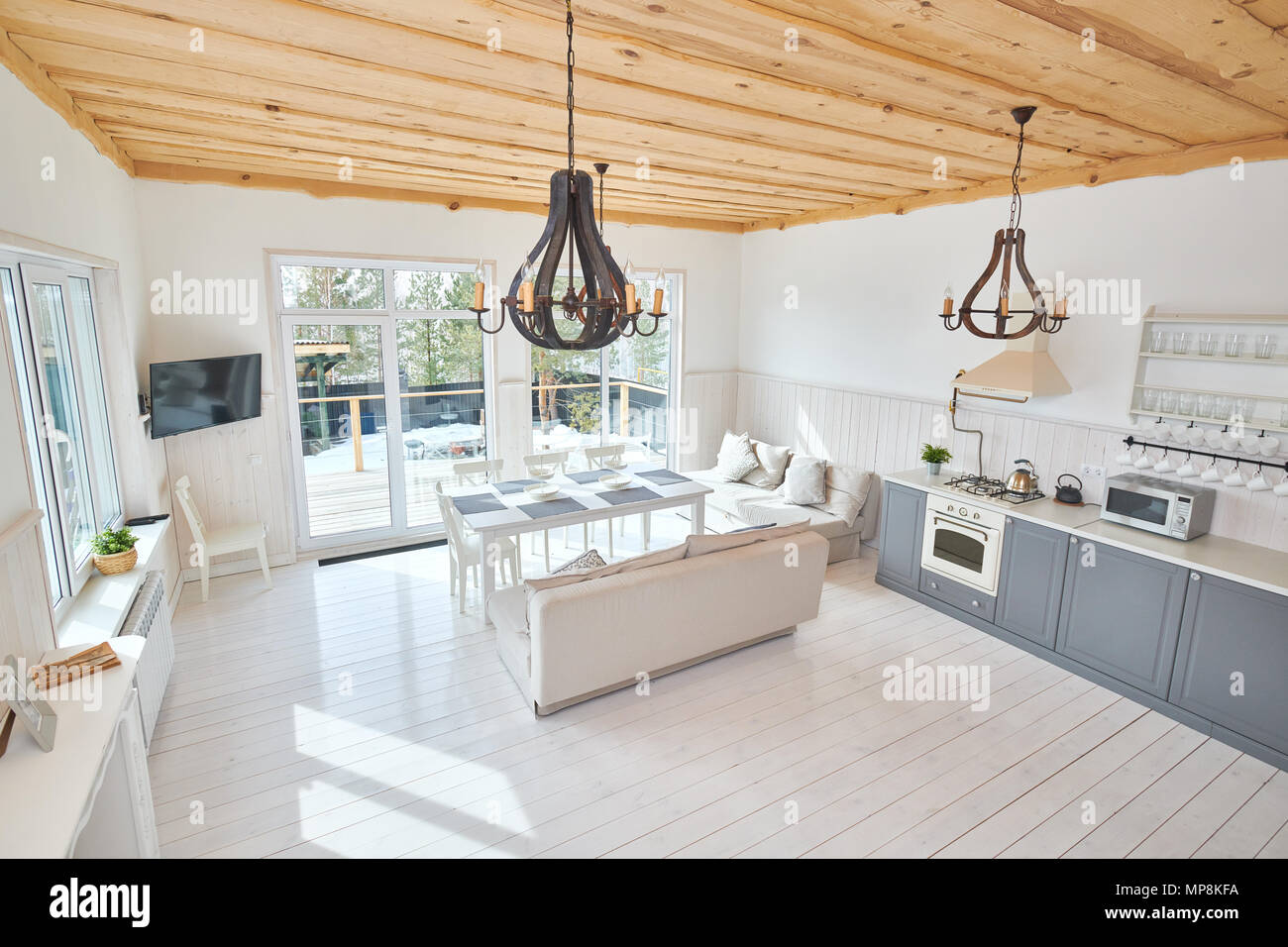 Weitwinkel von modernen offenen Wohnzimmer Innenraum mit Blick auf raumhohe Fenster mit weißen Möbeln und grau Küche Zähler in minimalistischer Sca Stockfoto