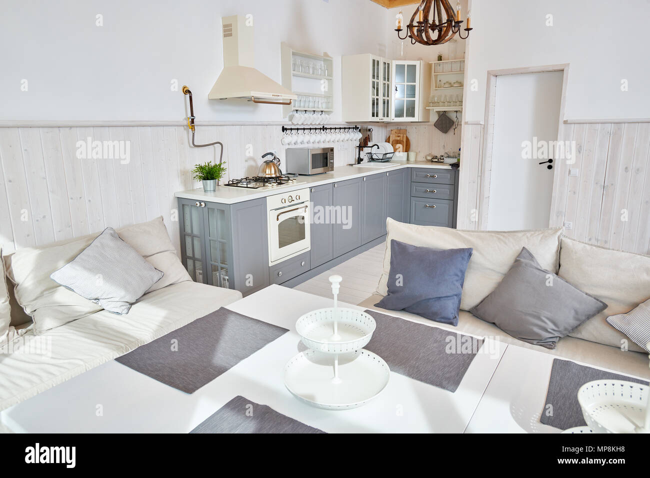 Offene Küche Einrichtung mit weißen Möbeln und grau Küche Zähler in minimalistischen skandinavischen Design durch Sonnenlicht, Kopie Raum beleuchtet, niemand Stockfoto