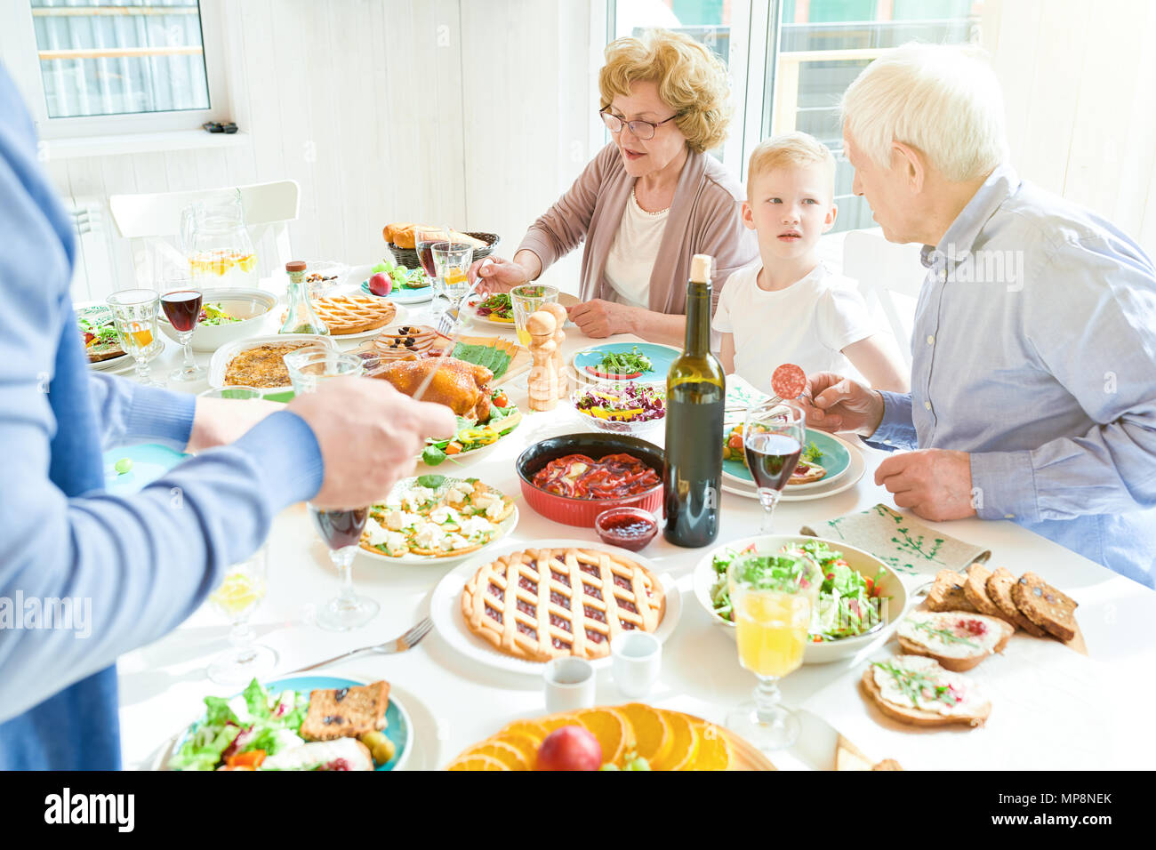 Großeltern genießen Familie Abendessen im Sonnenlicht Stockfoto