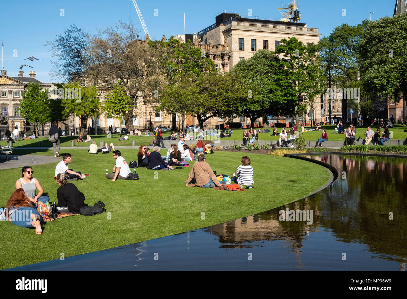 Leute sitzen auf Gras in St Andrews Square in warmen, sonnigen Wetter in Edinburgh, Schottland, Vereinigtes Königreich, Großbritannien Stockfoto