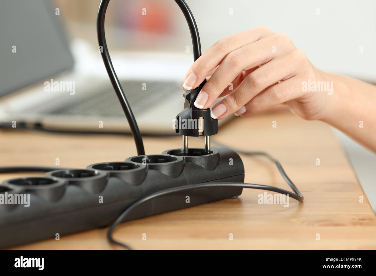 Nahaufnahme einer Frau die Hand Stecken Netzstecker ein in einem Sockel auf einem Tisch Stockfoto