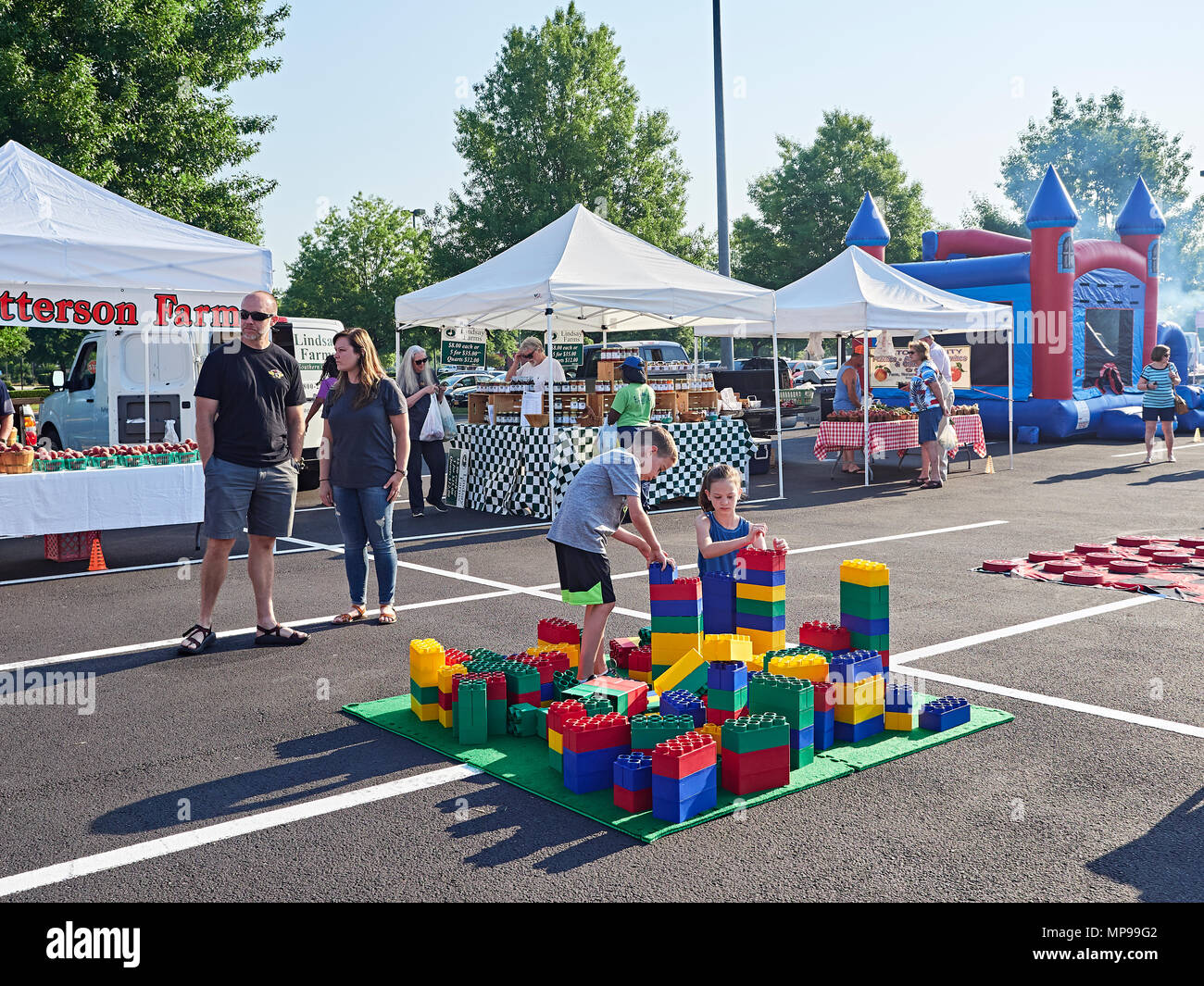 Junge und Mädchen Kinder spielen oder spielen mit riesigen Lego Bausteine ist ein Spaß für die ganze Familie Bauernmarkt mit ihren Eltern in Montgomery Alabama, USA beobachten. Stockfoto