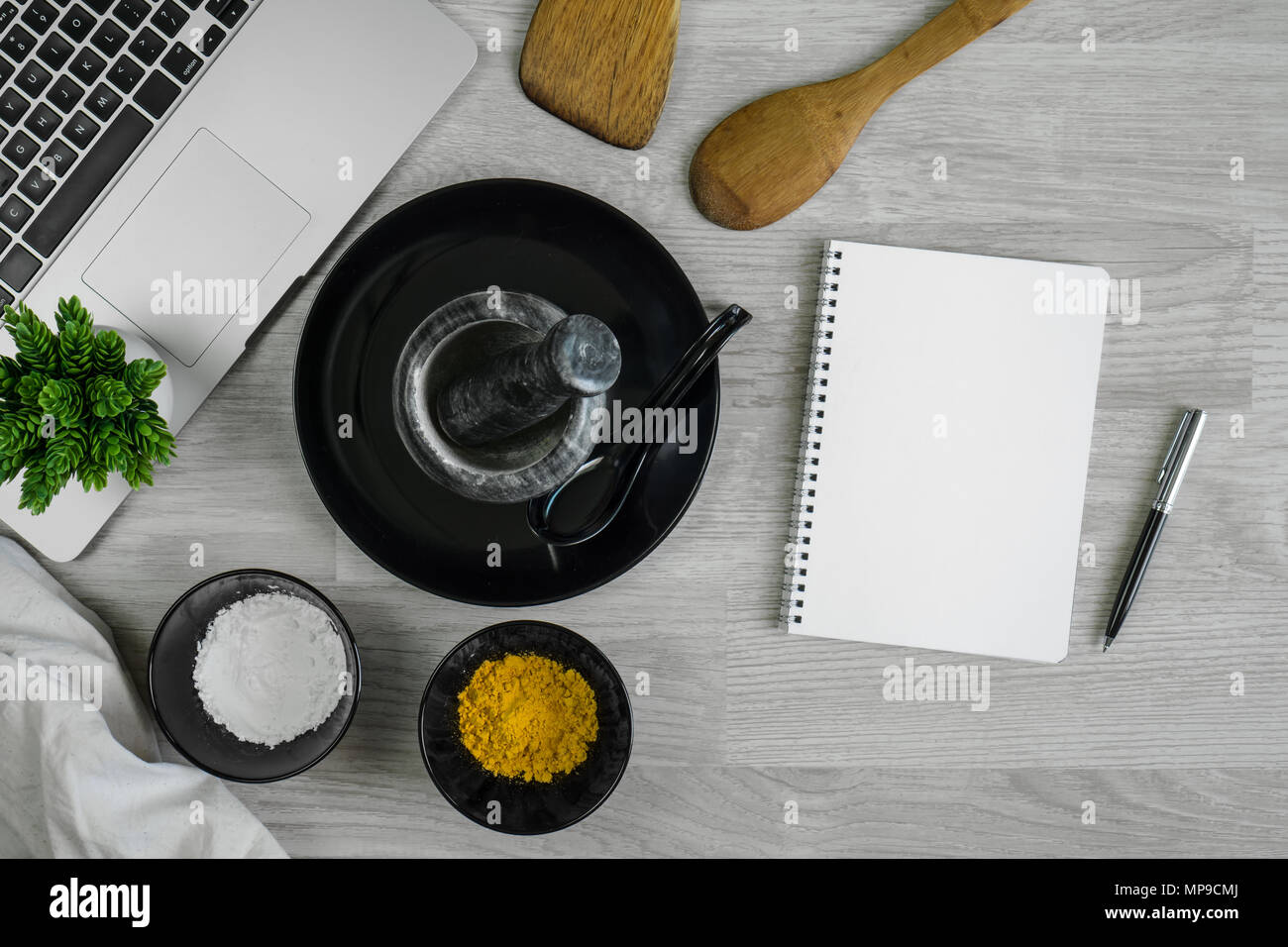 Besteck mit Gewürzen, Chilis, Mörtel, Laptops und Notebooks auf Holz Tabelle hinterlegt. Küchengeräte. Stockfoto