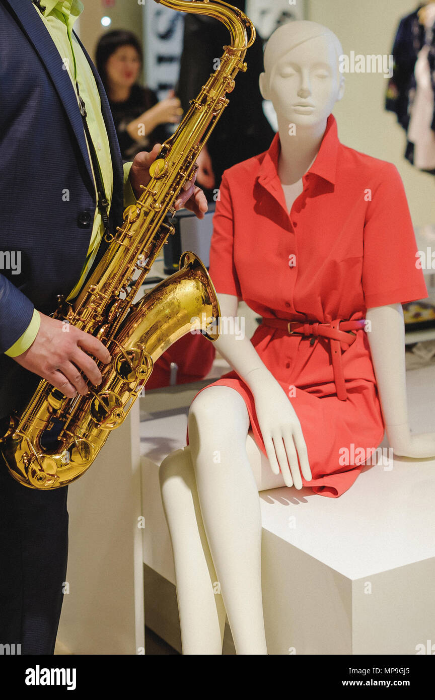 Musiker spielt das Saxophon Performance bei einem Konzert im Einkaufszentrum von Damenbekleidung Store auf Urlaub Stockfoto