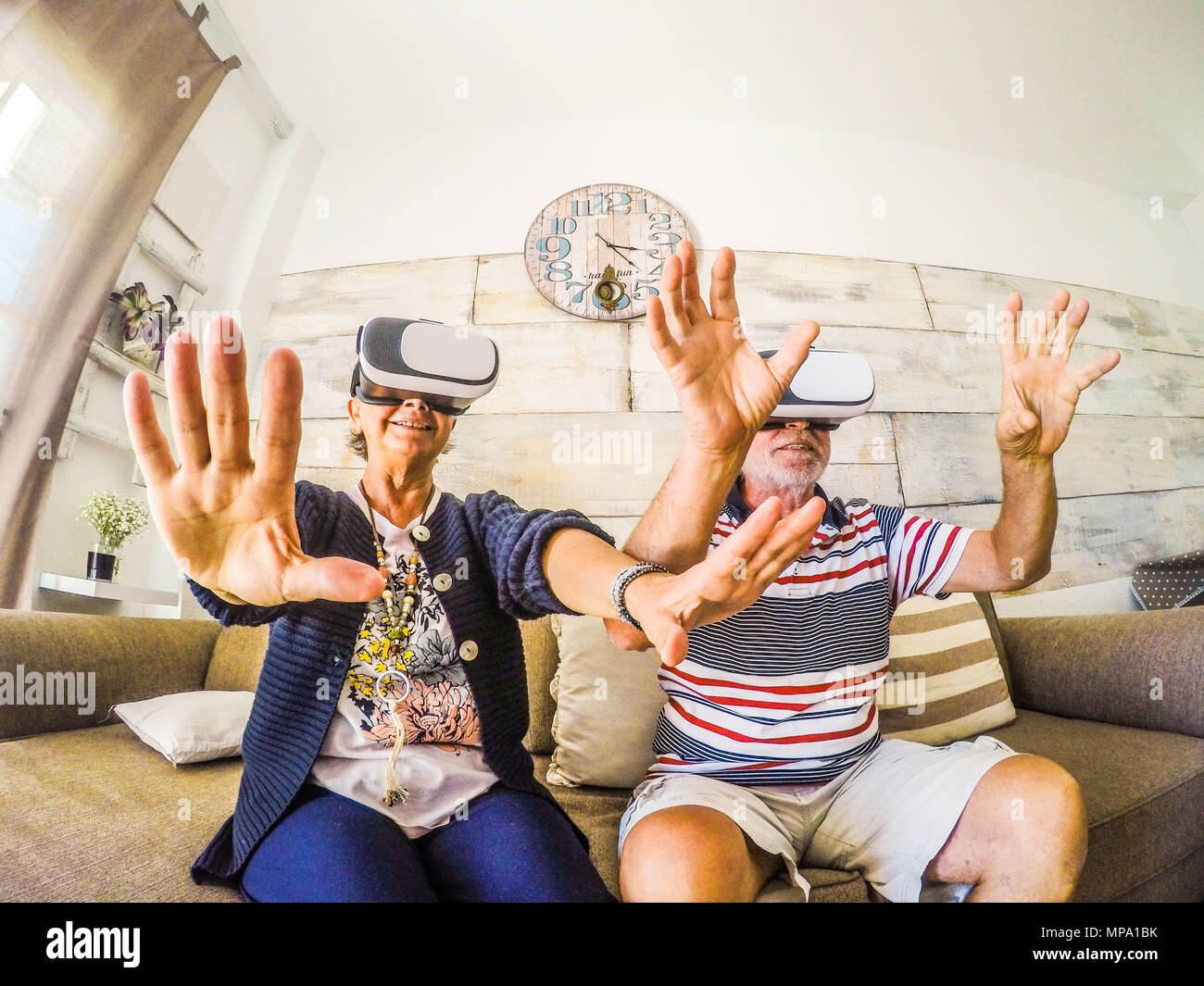 Paar der älteren Spielen bei Achterbahn mit Virtual reality Headset auf dem Sofa zu Hause sitzen. Glück für pensionierte Mann und Frau mit Goggle g Stockfoto