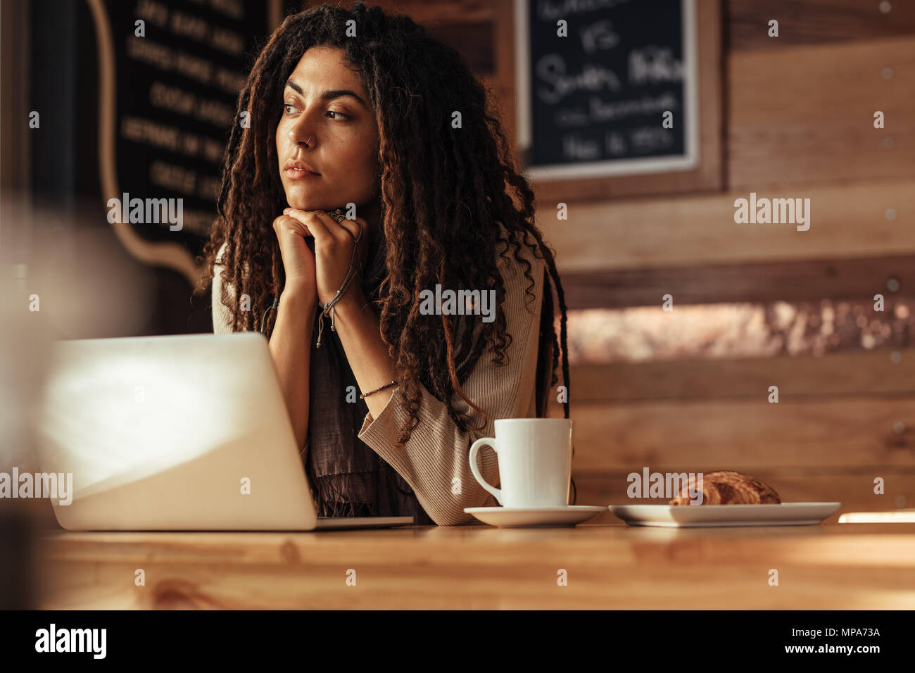 Frau Unternehmer in einem Restaurant ihr Kinn auf ihre Hände tief Denken. Freelancer sitzen im Café mit Kaffee und Snacks auf der Arbeit Stockfoto