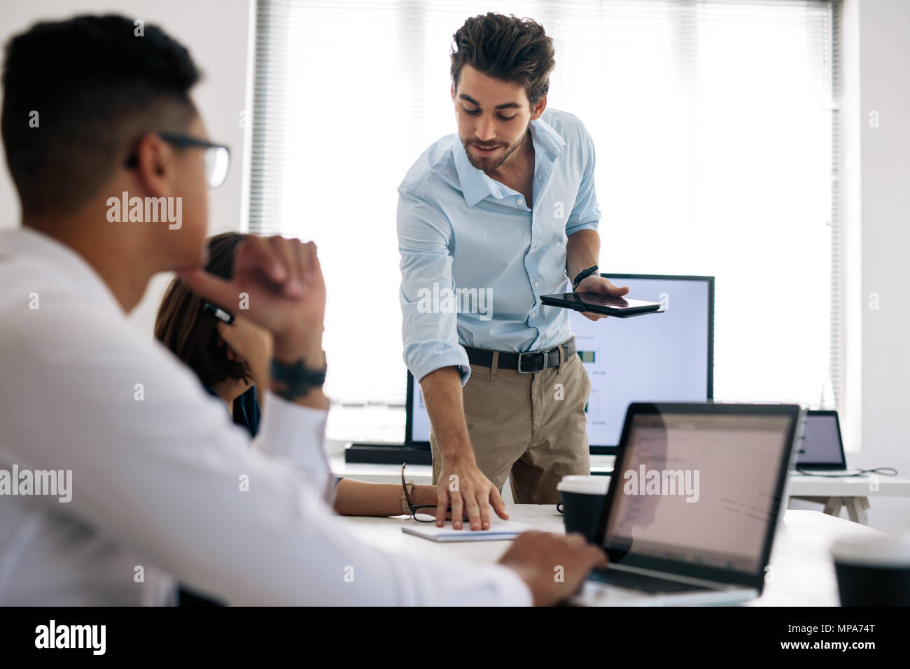 Geschäftsmann eine Darstellung an seine Kollegen im Büro. Büro Kollegen bei Laptops während einer Präsentation Stockfoto