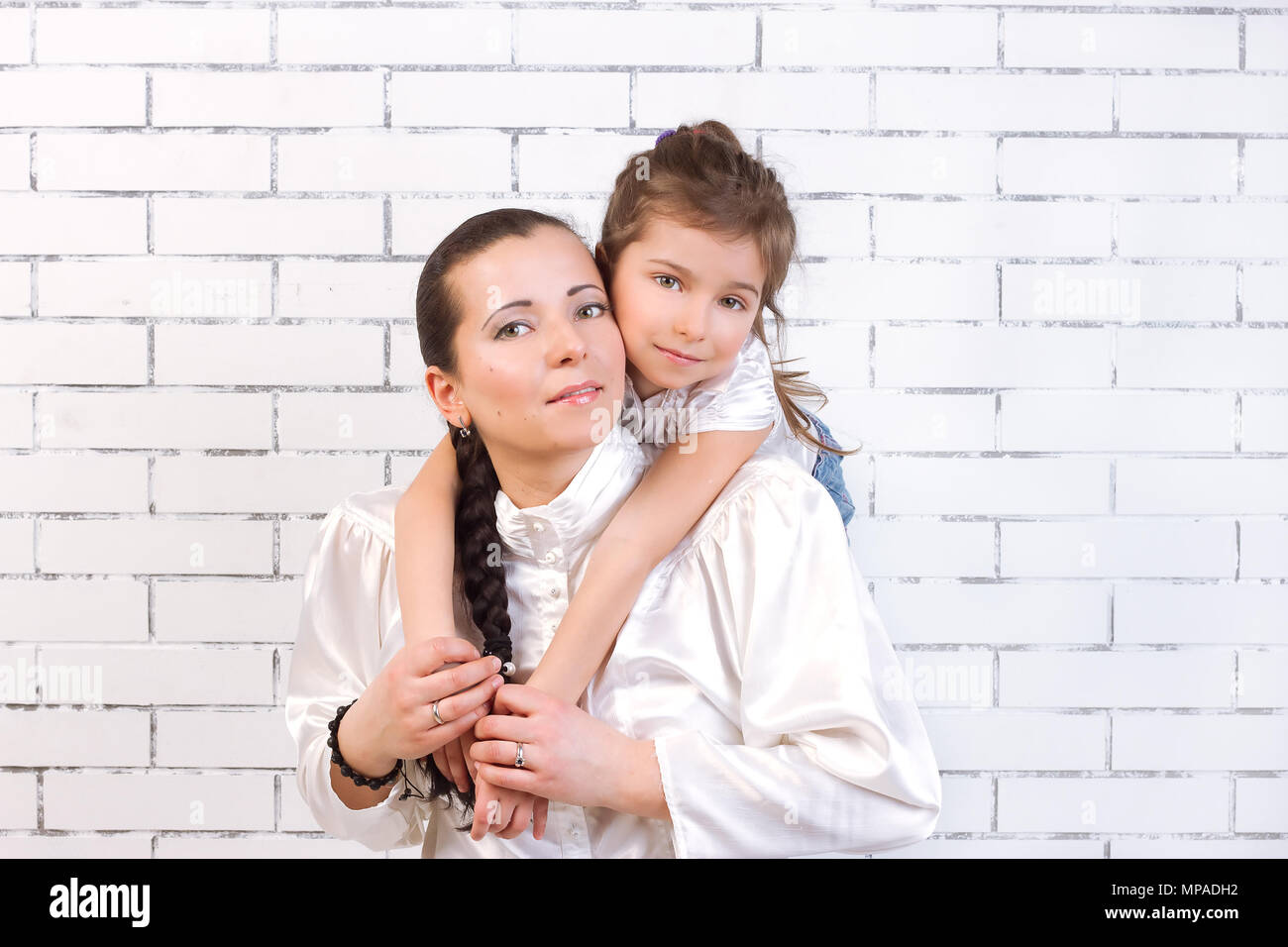 5 Jahre alten Tochter in einem weißen Kleid sanft umarmt seine Mamma Stockfoto