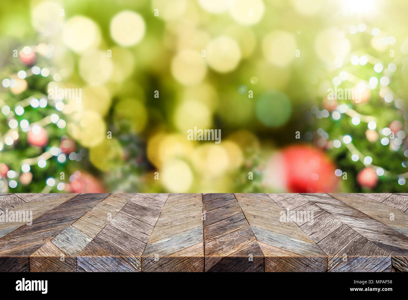 Leere dunkelbraunem Holz Tischplatte mit Abstract blur Weihnachtsbaum rot Dekor Kugel und Schneefall Hintergrund mit bokeh Licht, Winterurlaub Kulisse, Moc Stockfoto