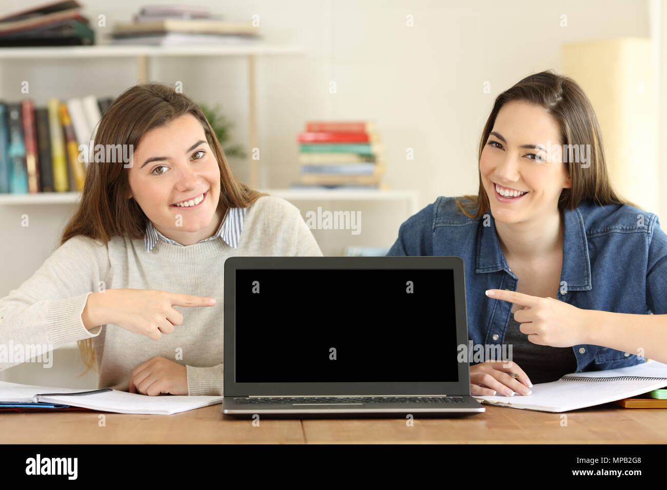 Vorderansicht Portrait von zwei Studenten an einem Laptop Bildschirm Mockup zu Hause zeigen Stockfoto