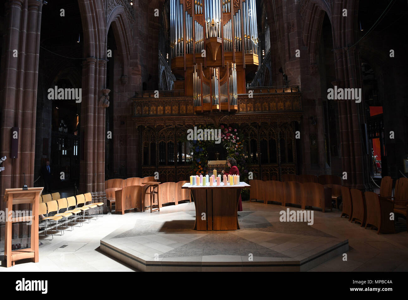 Ein Mitglied des Klerus leuchten Kerzen für die Opfer während der Manchester Arena National Service der Gedenkfeier in der Kathedrale von Manchester zu einem Jahr seit dem Angriff auf Manchester Arena. Stockfoto