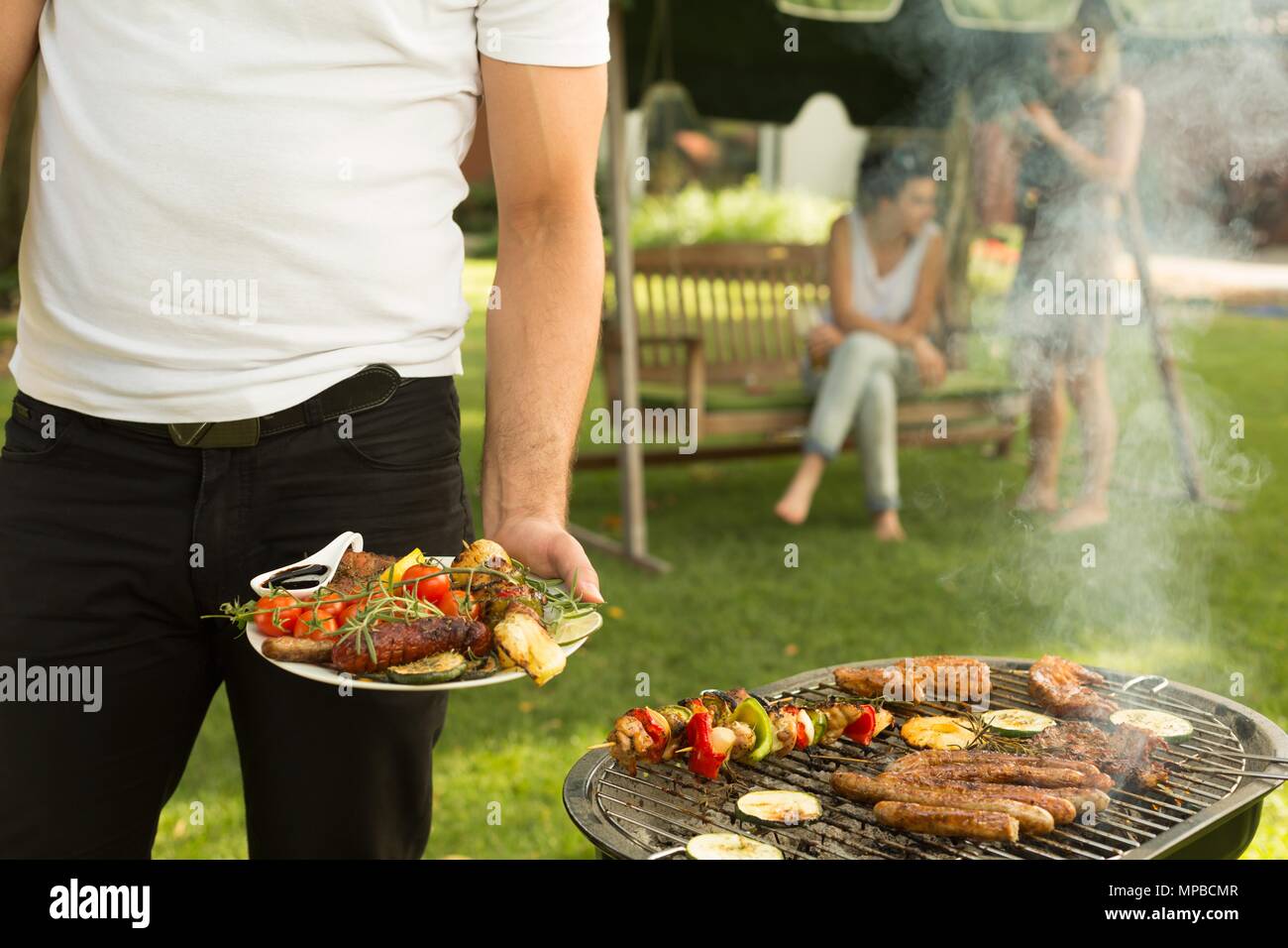 Mann hält Teller voll von gegrillten Speisen Stockfoto