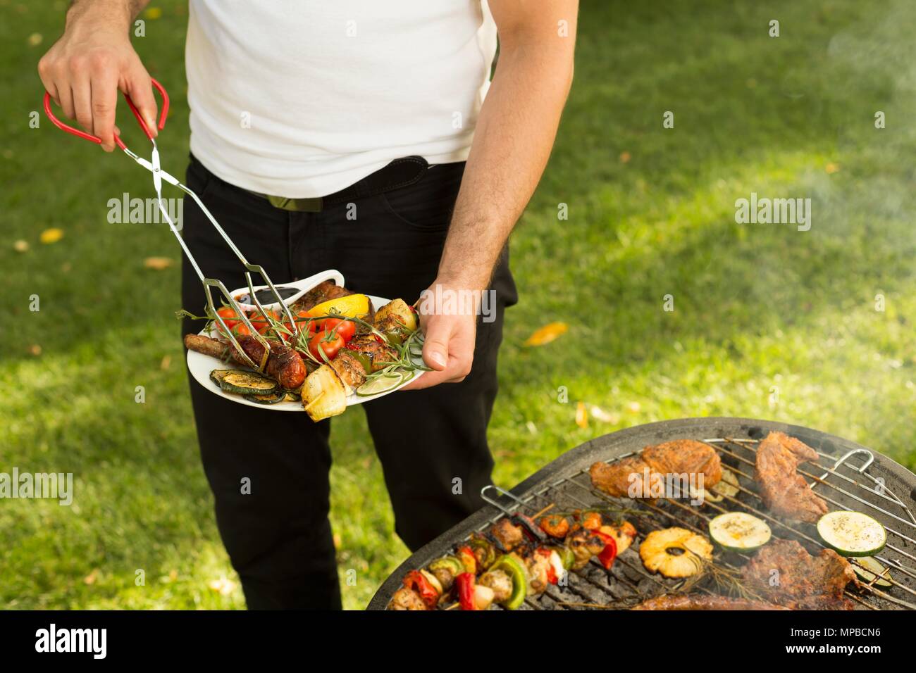 Der Mann hält eine Platte voller Grill essen Stockfoto