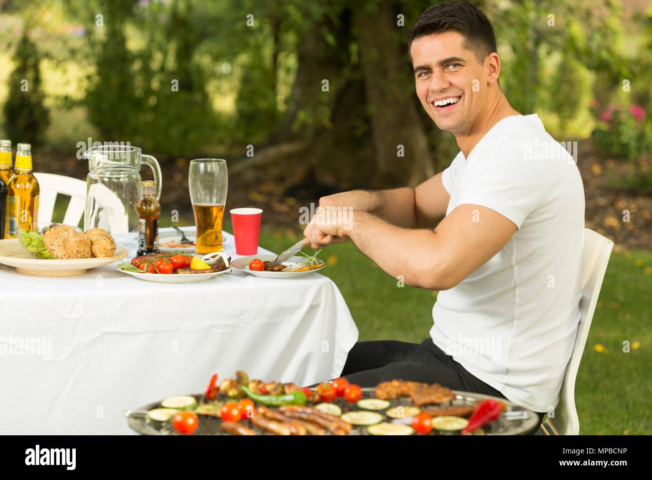 Schöner Mann außerhalb in Sommer Barbecue Dinner Stockfoto