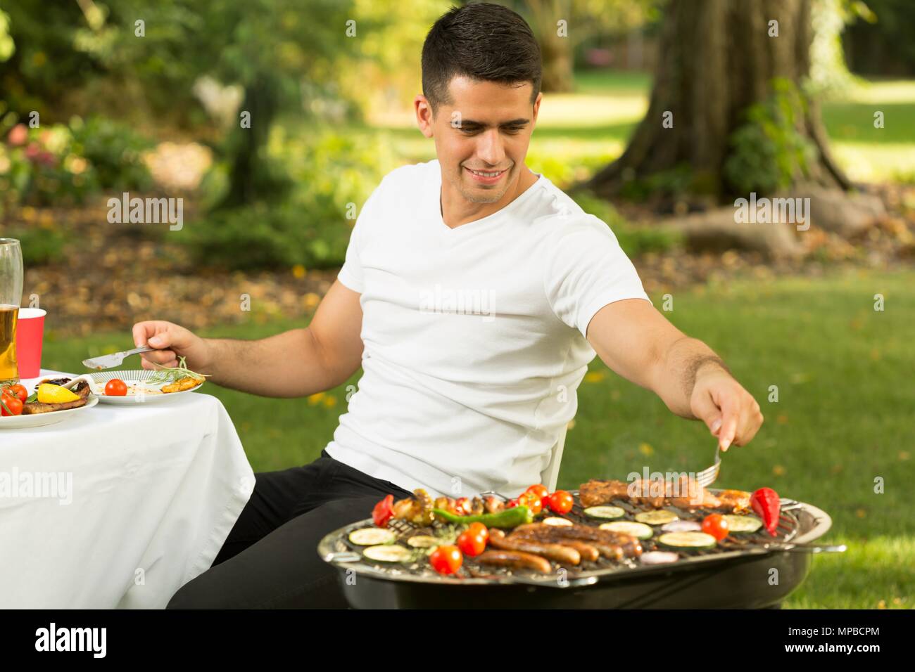 Hungrigen jungen Mann die Sekunden der Grill essen Stockfoto