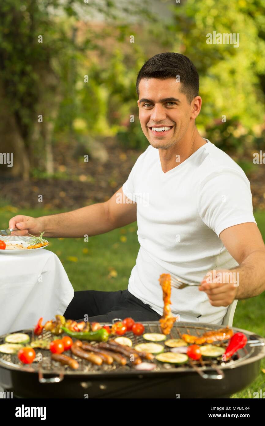 Schoß eines jungen gutaussehenden Mann grillen im Garten Stockfoto