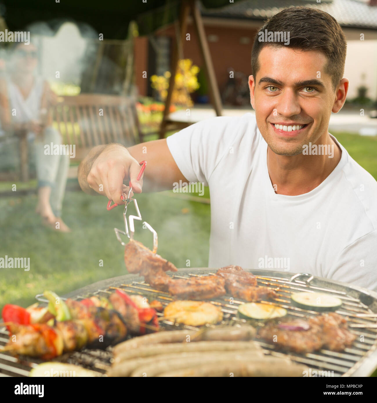 Schön lächelnden Mann Vorbereitung Grill Speisen zum Abendessen Stockfoto