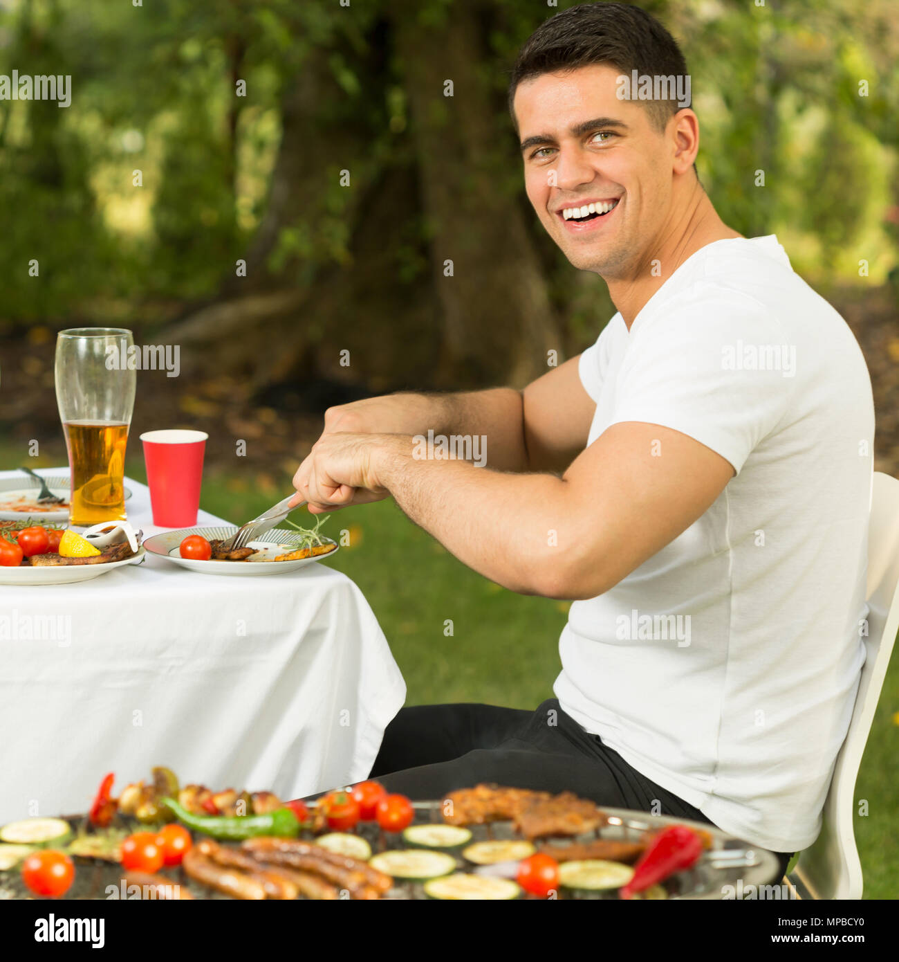Schöner Mann außerhalb in Sommer Barbecue Dinner Stockfoto