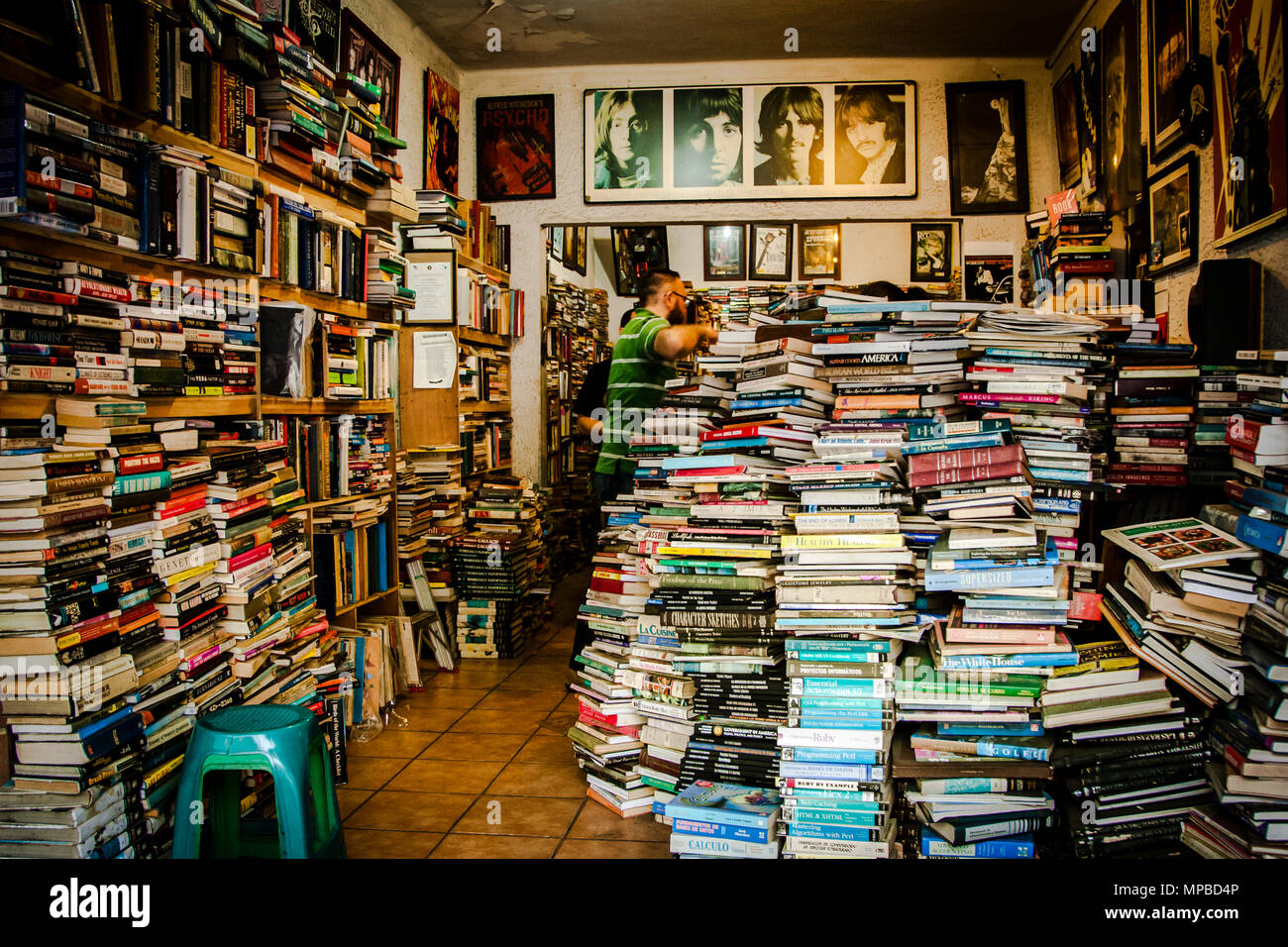 Book Shop in San Jose, Costa Rica mit Stapel von Büchern gefüllt in den Regalen und auf dem Boden. Im Hintergrund können Sie Porträts der Beatles zu sehen. Stockfoto