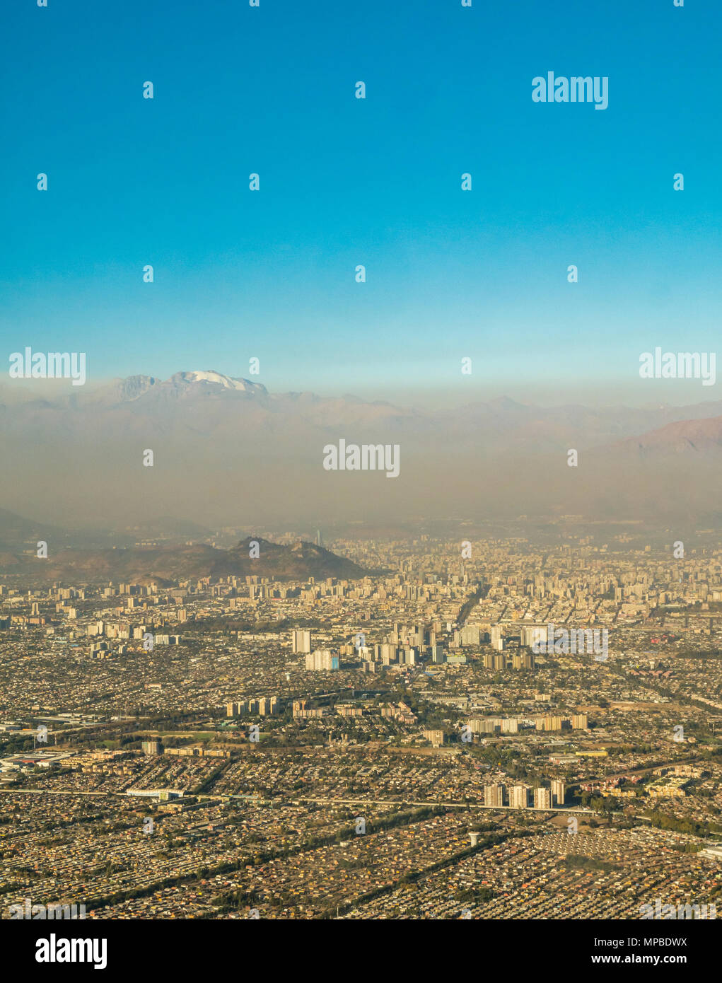 Blick auf Santiago, Chile aus dem Flugzeug Fenster mit Cerro San Cristobal und schneebedeckten Anden über Schicht von Smog und Luftverschmutzung Stockfoto