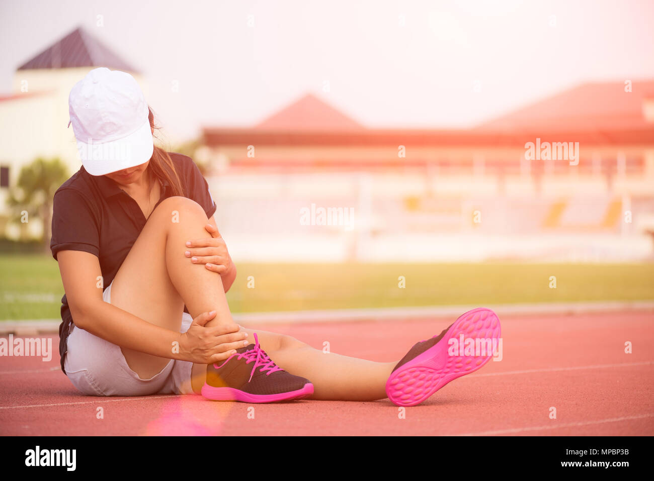 Knöchel verstaucht. Junge Frau mit einer Knöchelverletzung beim Trainieren und laufen auf der Laufstrecke. Gesundheit und Sport Konzept. Stockfoto