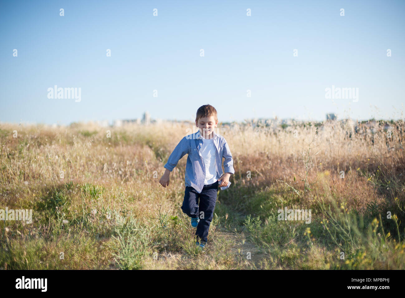 Glücklich lächelnde Junge wandern unter gelben Gras im Sommer sonnigen Tag Stockfoto
