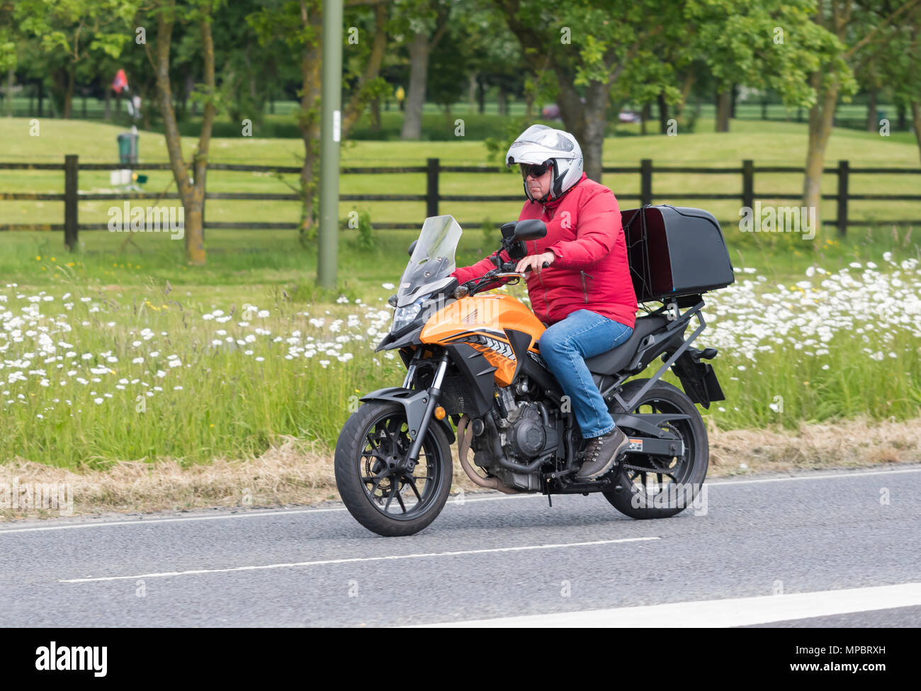 Im mittleren Alter Mann, ein Honda Motorrad in den letzten äußeren Spur einer zweispurigen Straße in Großbritannien. Stockfoto