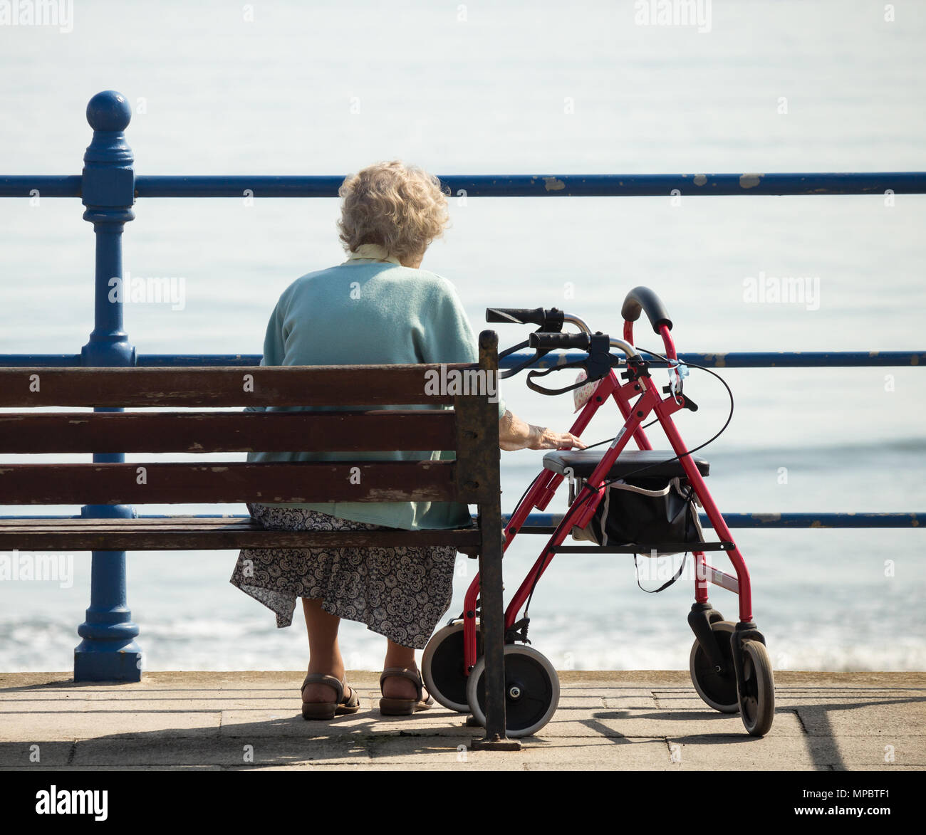 Ältere Frau sitzt auf der Bank mit Blick auf das Meer. Großbritannien Stockfoto