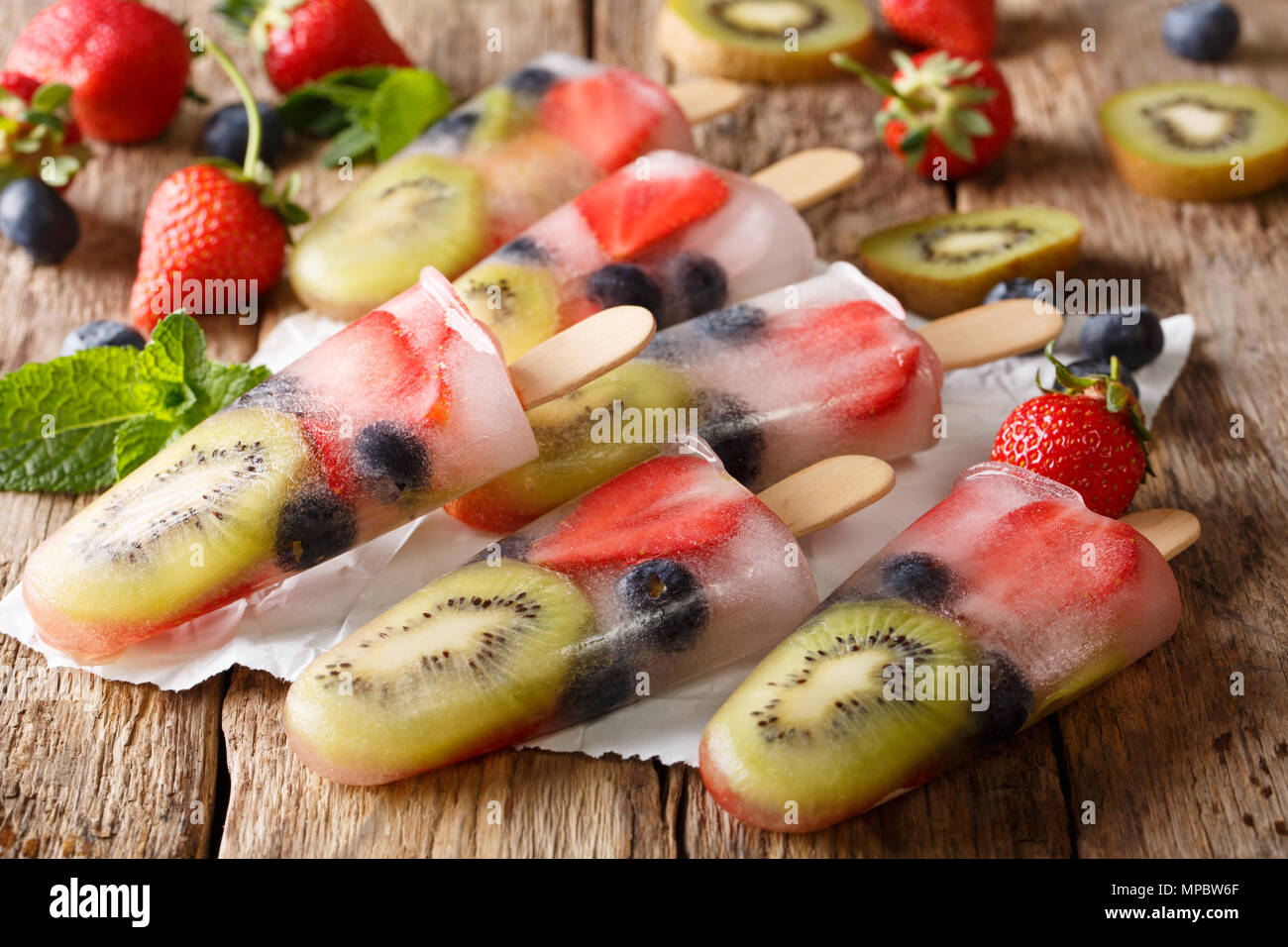 Gefrorenen Saft mit frischen Erdbeeren, Kiwi und Heidelbeeren auf einem Stock close-up auf dem Tisch. Horizontale Stockfoto