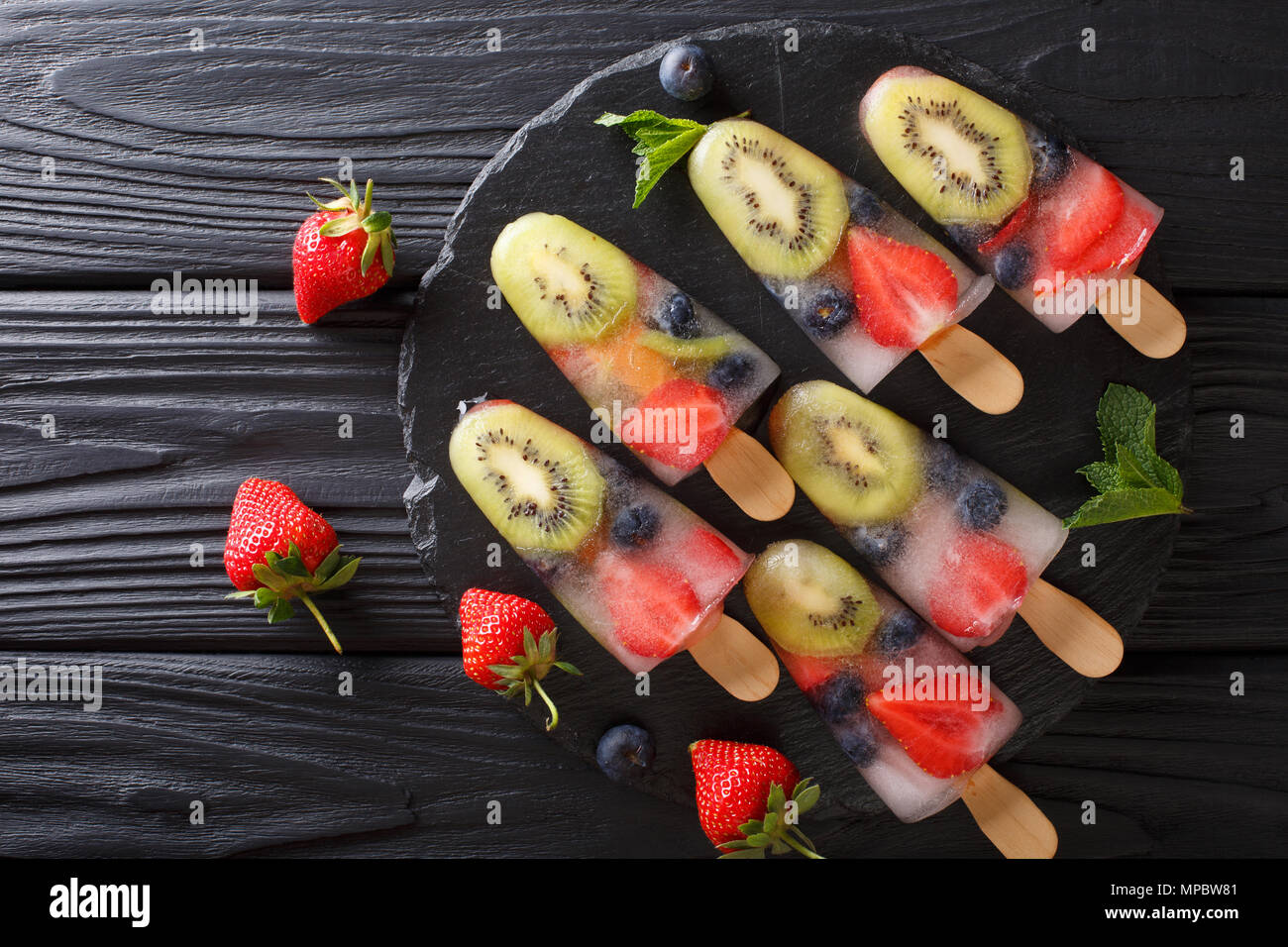 Berry Obst Eis am Stiel Eis aus frischen Erdbeeren, Kiwi und Blaubeeren mit Minze Nahaufnahme auf dem Tisch. Horizontal oben Ansicht von oben Stockfoto