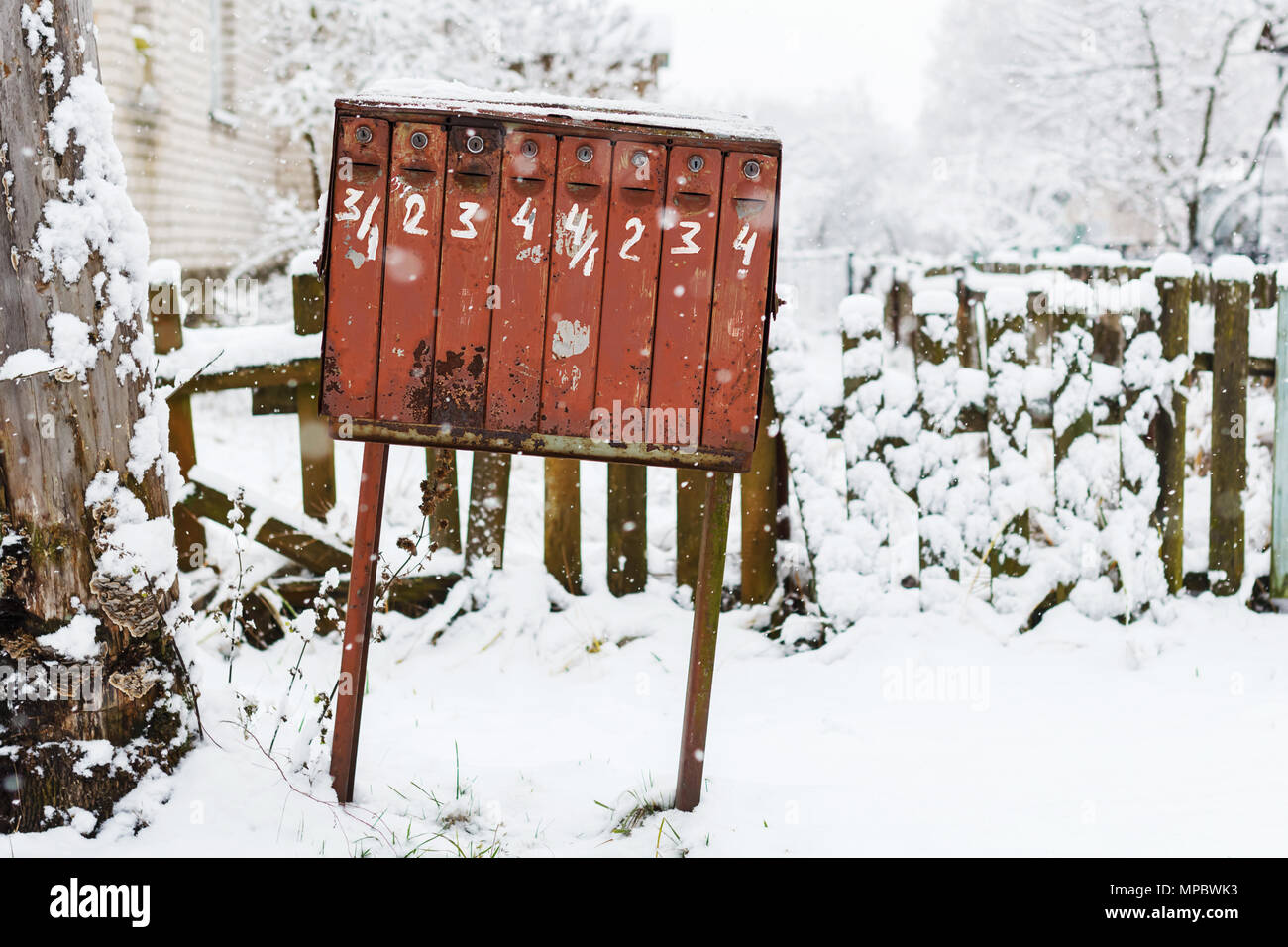 Alte klapprige Mailbox im Winter unter dem Schnee. Mailbox mit schriftlicher Zahlen und abblätternde Farbe Stockfoto