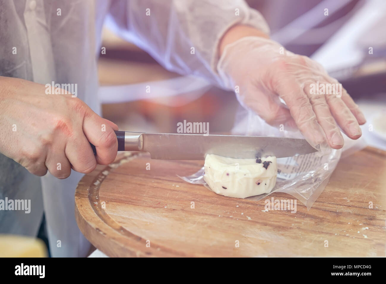 Verkäufer Schnitte, verkauft Käse mit Trüffel, Käse, Köpfe auf Holz zu schneiden. Hände mit Messer schließen. Gastronomische Milchprodukte, realen Szene, essen Markt Stockfoto