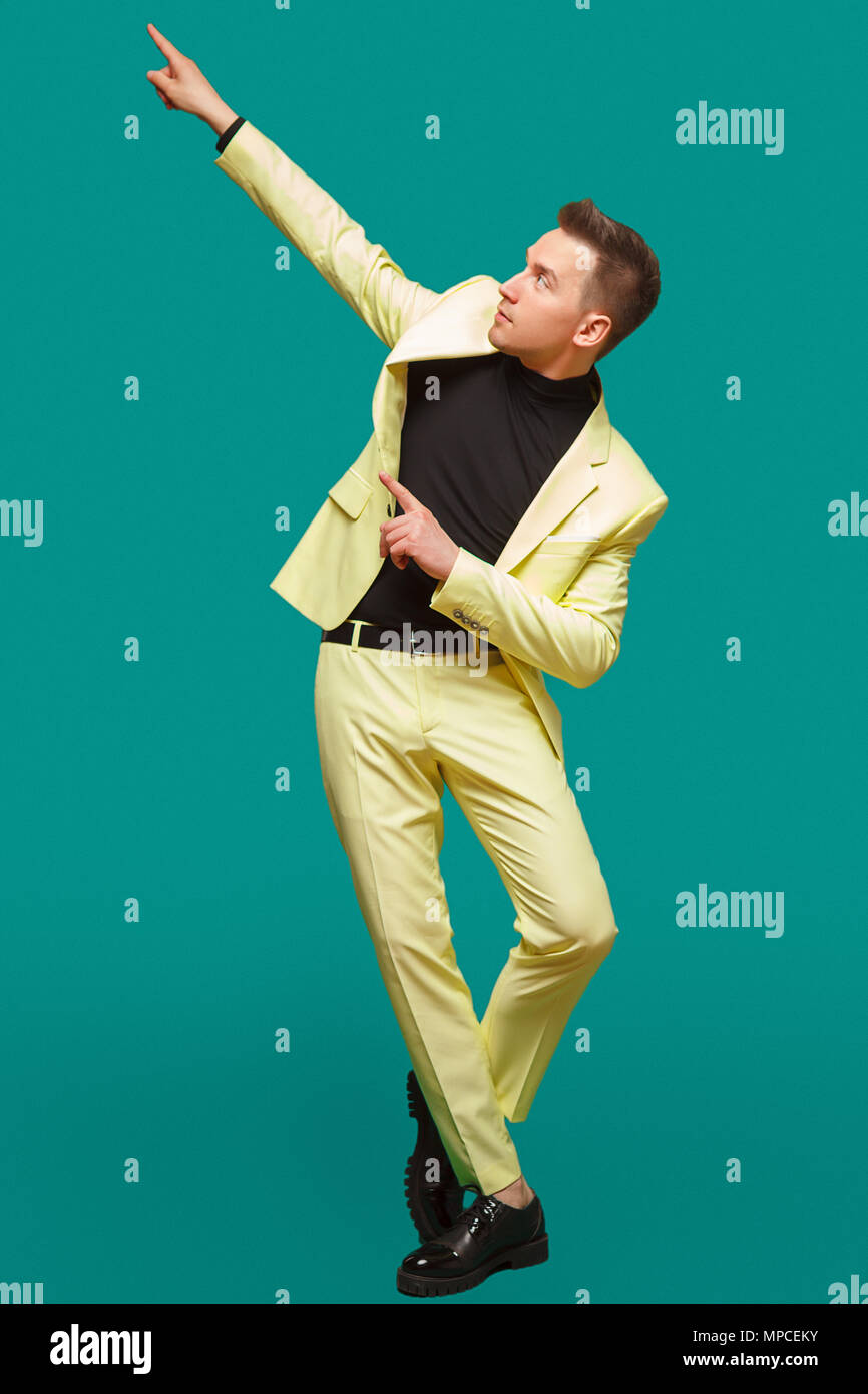 Attraktiven jungen Mann in Anzug tanzen, Spaß auf Minze Hintergrund. Stilvolle Outlook, erfolgreicher Geschäftsmann, glücklich, mit dem Ausdruck true positive Emotionen Stockfoto