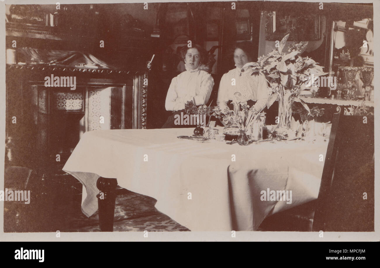Alte Ansichtskarte von zwei Damen saßen an einem Tisch in einem Grand House Stockfoto