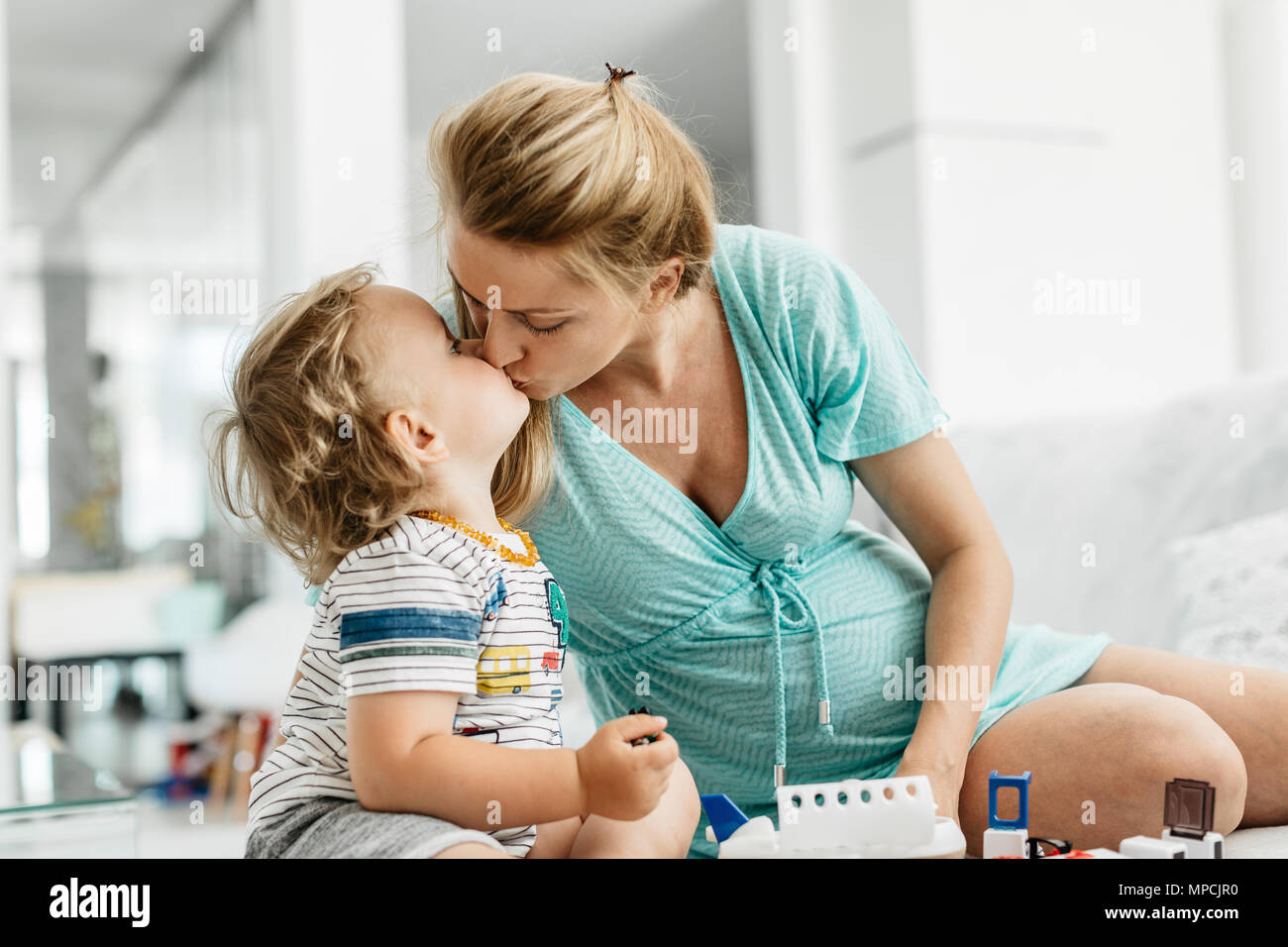 Der Mutter und dem Kind zu küssen. Ein Porträt einer schwangeren Frau mit ihr spielen Toddlersohn und zärtliche Momente. Stockfoto