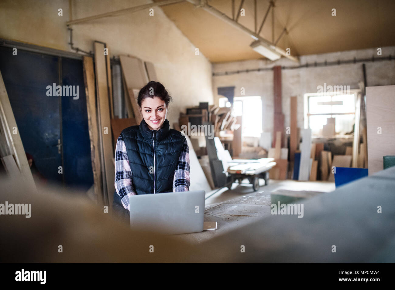 Porträt einer Frau, die Arbeiter mit Laptop in der Schreinerei. Stockfoto