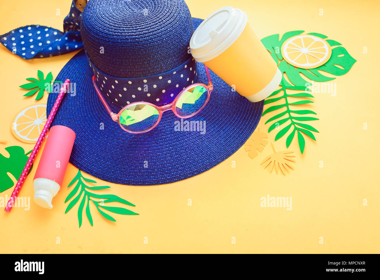 Beach Hut, Sonnenbrille, Lotion, erfrischendes Getränk und tropische Blätter auf einem gelben Hintergrund. Sommer Urlaub Konzept mit kopieren. Stockfoto