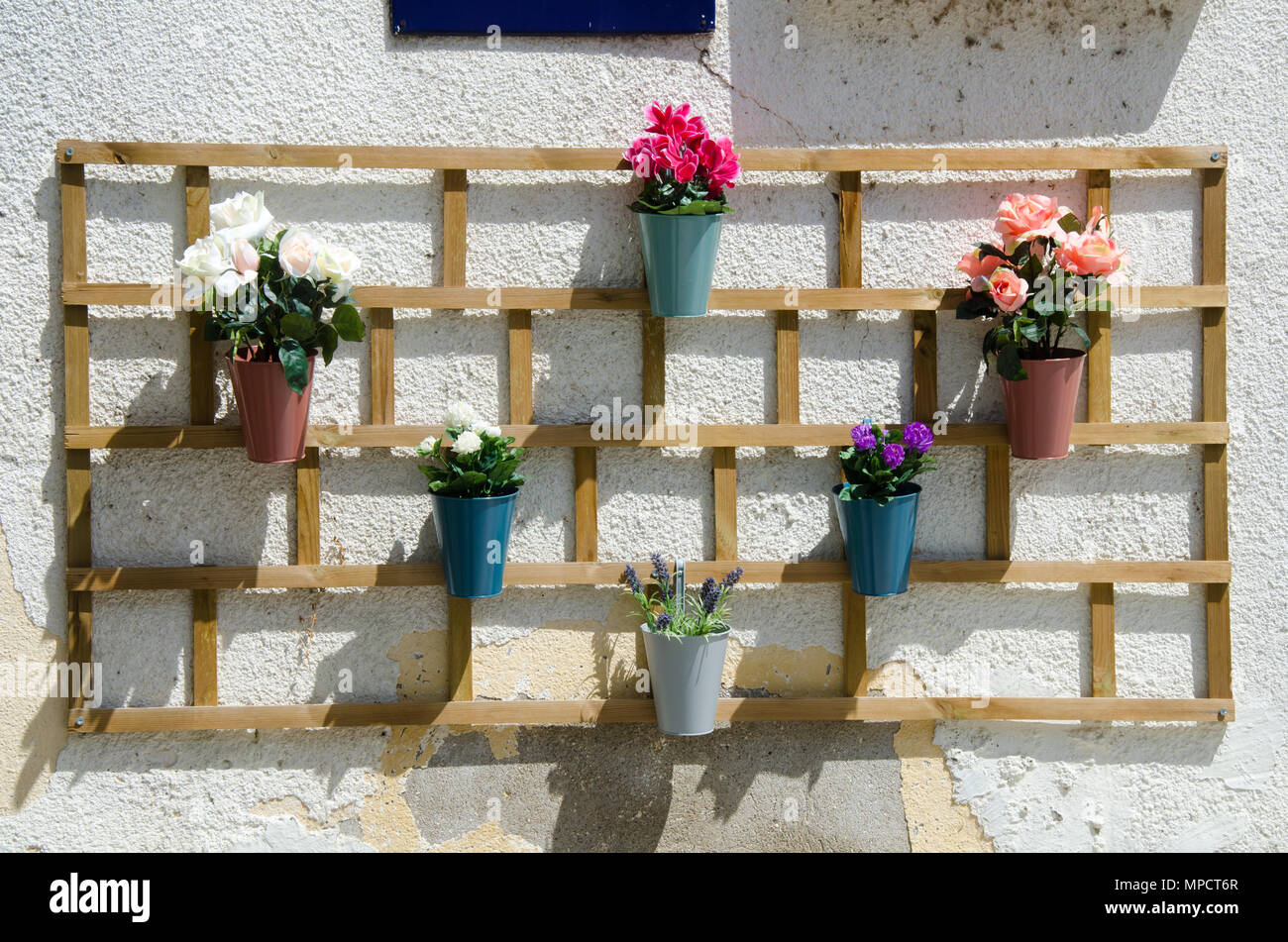 Interessante Holzregal für Blumentöpfe mit bunten Blumen, die auf der  weißen Wand des Hauses, Outdoor Dekoration Stockfotografie - Alamy