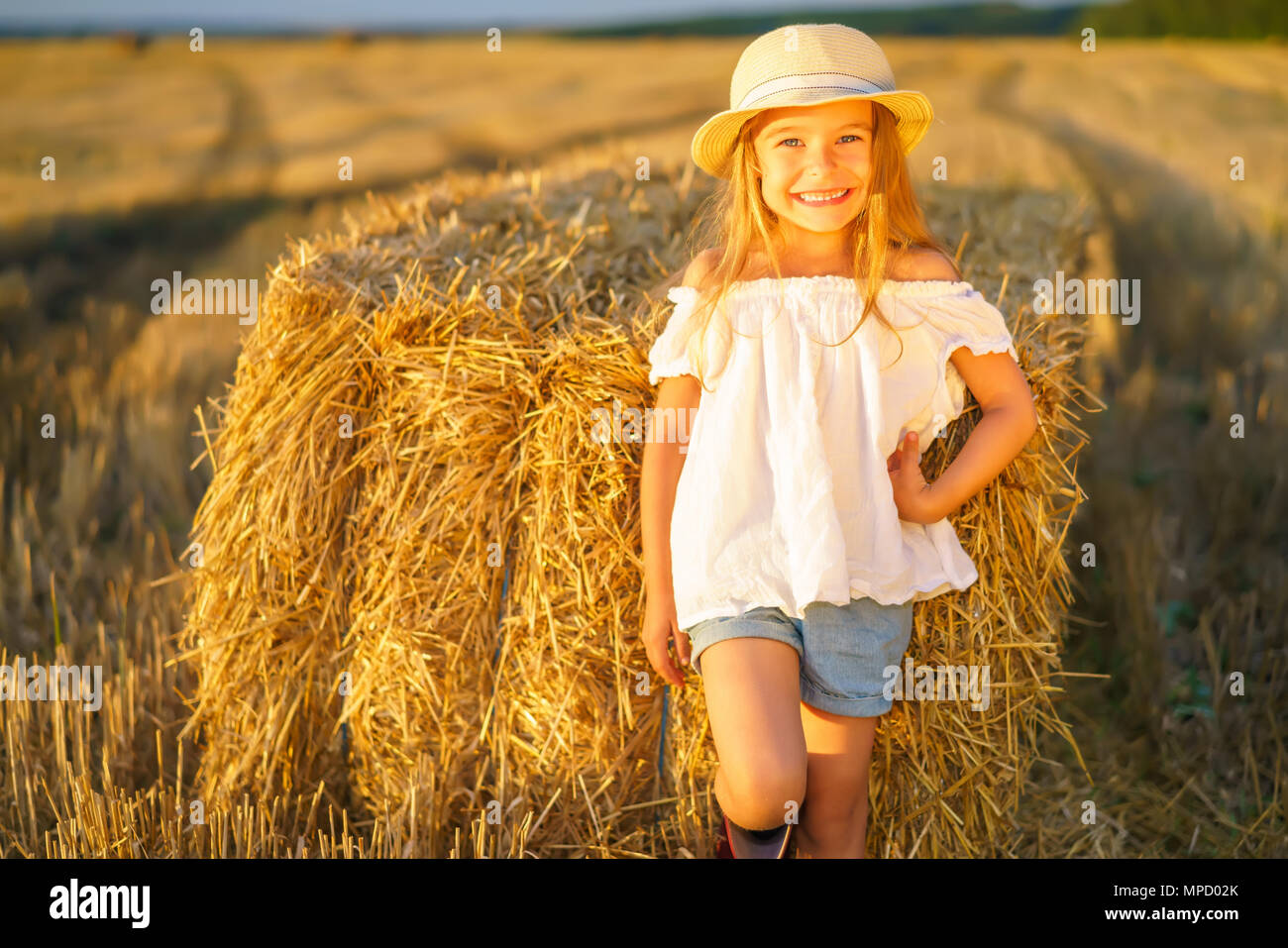 Kleines Mädchen in einem Feld mit Heu Rollen Stockfoto