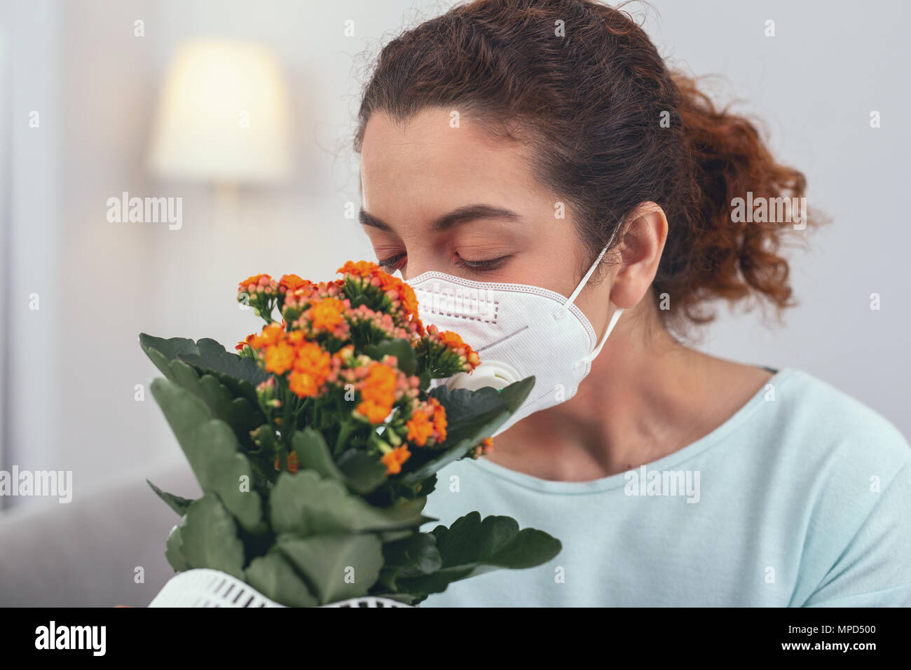 Junge Mädchen einen Geruch potted Flower beim Tragen einer Atemschutzmaske Stockfoto
