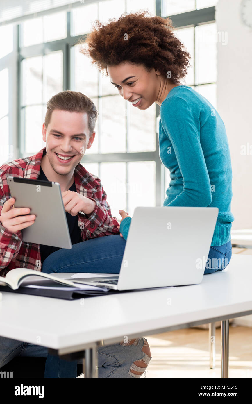 Zwei glückliche Schüler beobachten ein lustiges Video auf einem Tablet PC während der Pause Stockfoto