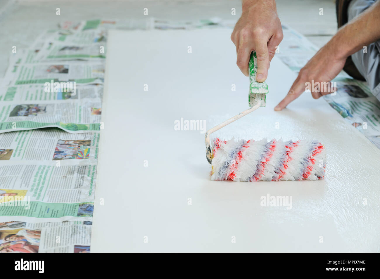 Arbeitnehmer Einfügen von Hintergrundbildern. Er Leim mit einer Rolle. Stockfoto