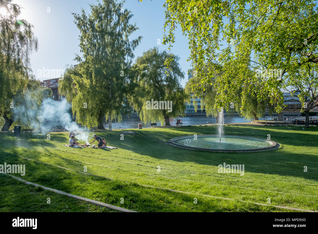 Die Menschen genießen ein Picknick im Park am Wasser entlang Strömparken Fluss Motala in Norrköping im Frühjahr in Schweden. Stockfoto