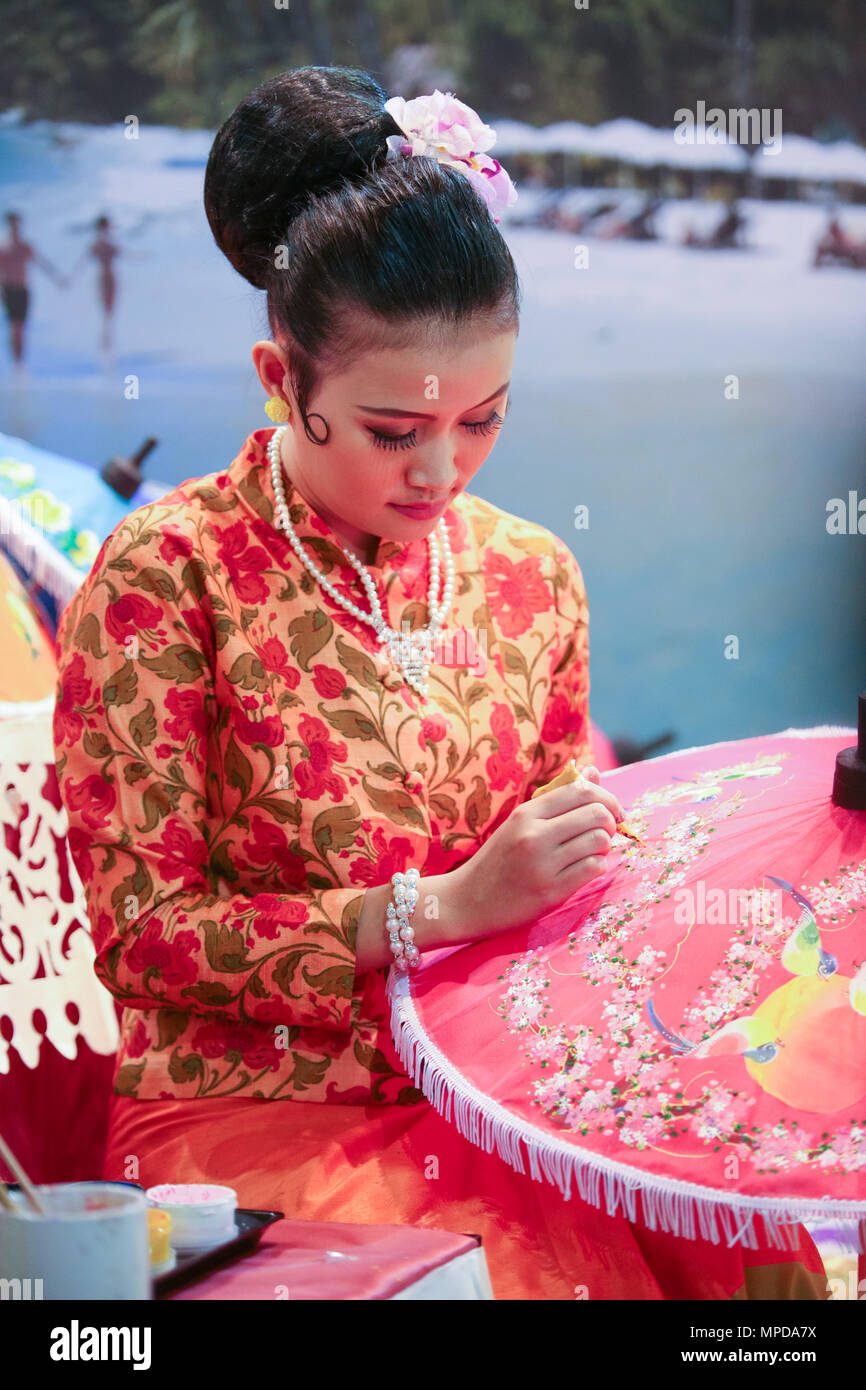 Thai craftwoman präsentiert die klassische Methode der Umbrella Malerei an einer Thailand Tourismus Ausstellung. Stockfoto