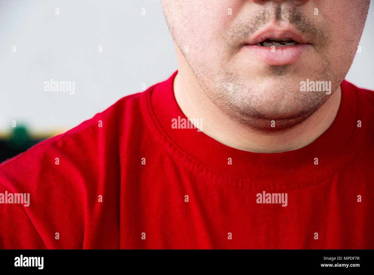 Unrasierten Mann im roten T-Shirt ohne Emotion Stockfoto