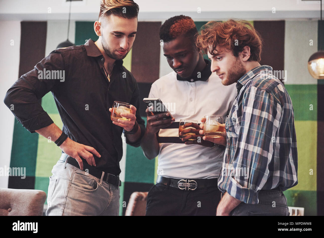 Vielversprechende junge multi-ethnische Menschen feiern und trinken Whiskey Toast, Watch gadget Stockfoto