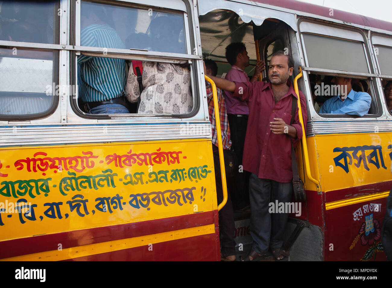 India, West Bengal, Kalkutta, ein Busfahrer steht im Fußraum eines öffentlichen Bus. Stockfoto