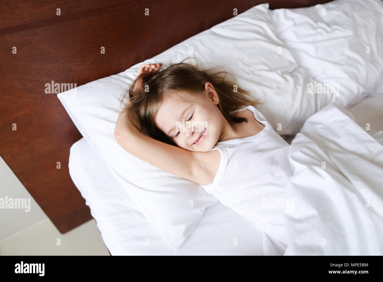 Kleines Mädchen schlafen am Morgen vor der Schule auf dem Bett mit weißer  Bettwäsche Stockfotografie - Alamy