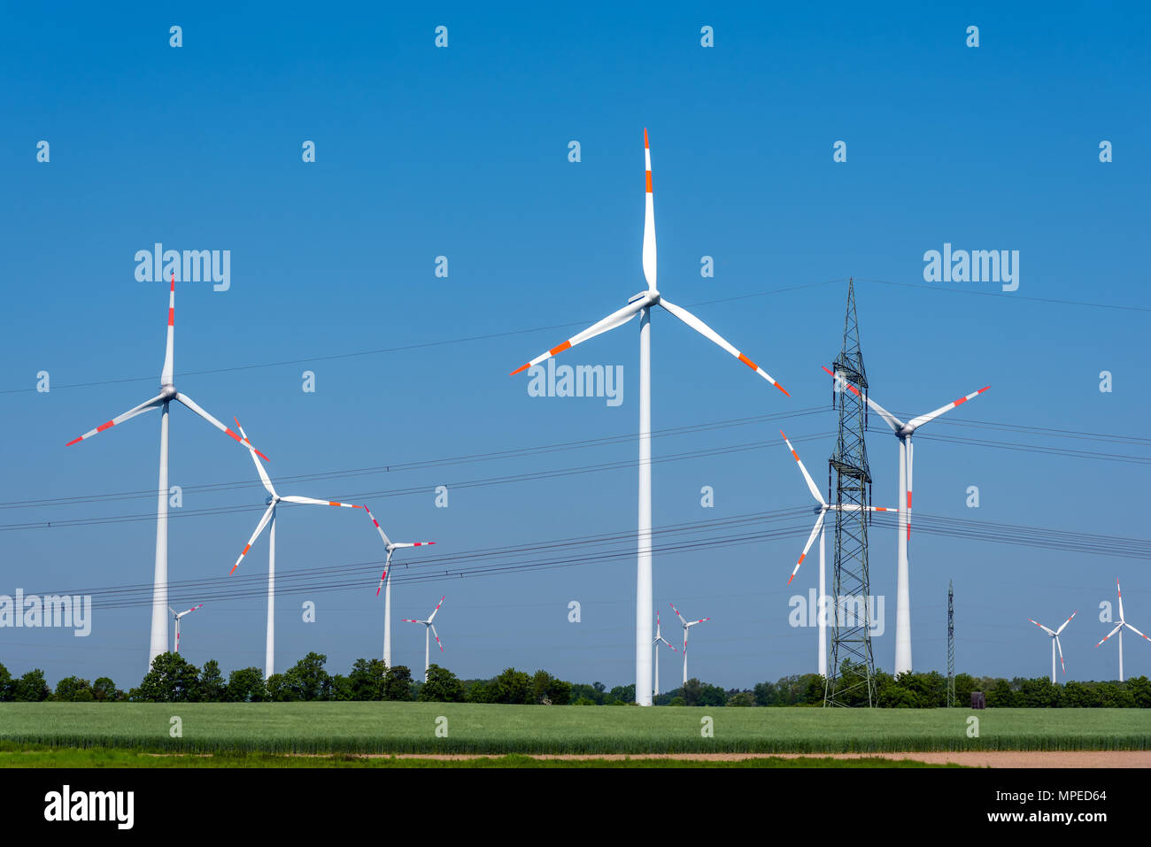 Freileitungen und Windkraftanlagen unter einem blauen Himmel in Deutschland Stockfoto