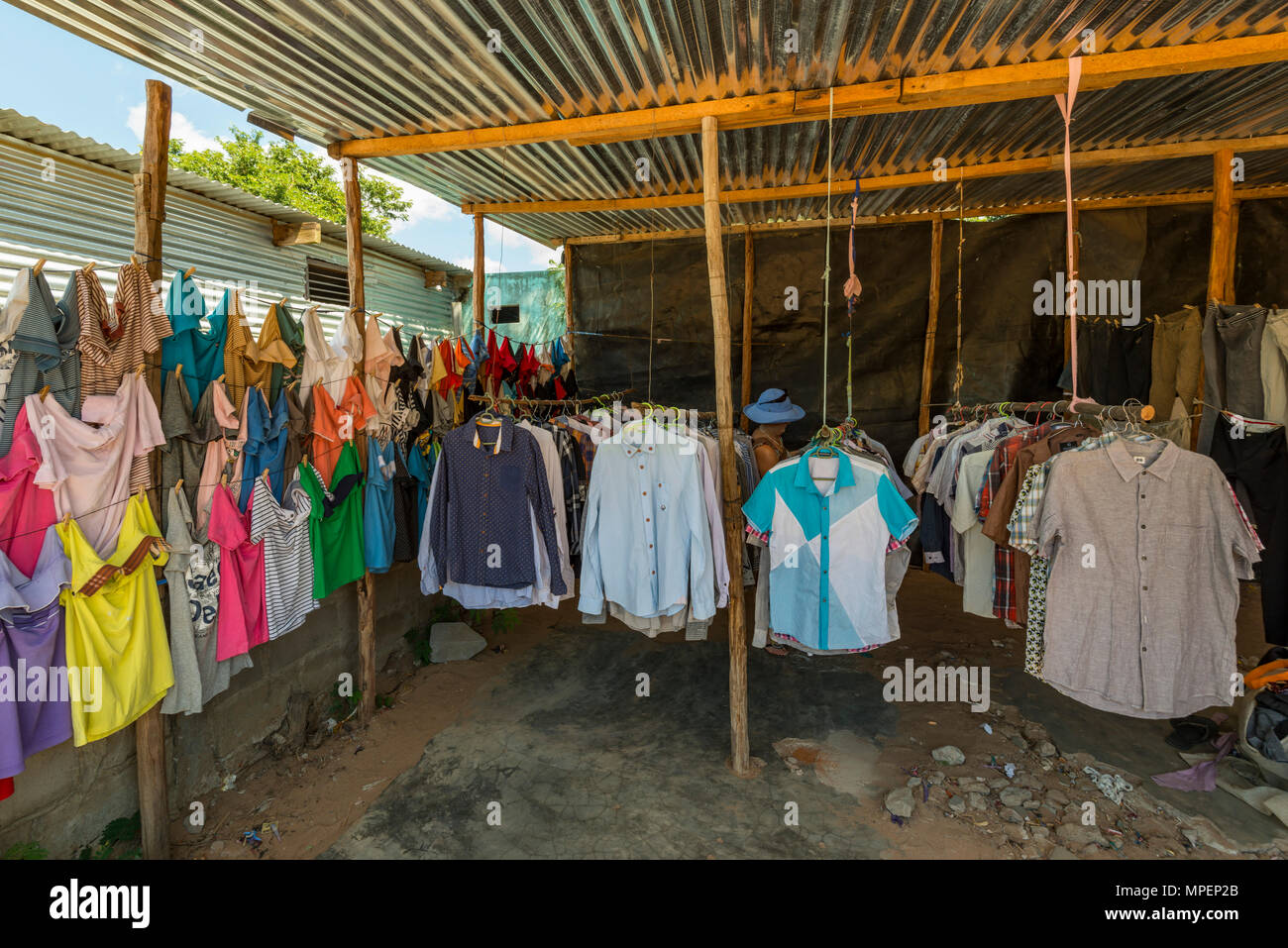 Ein Tourist durchstöbert Kleidung in einem informellen Geschäft in Inhassoro Mosambik. Stockfoto